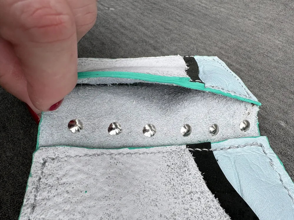 Wallet opened flat with a finger lifting up to show inner pockets.